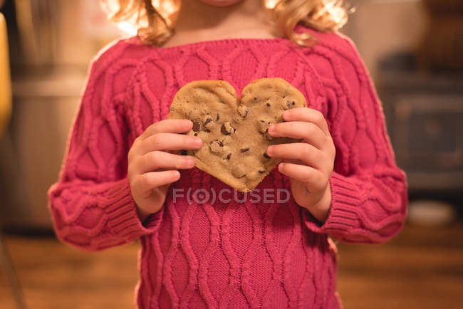 Seção média de menina segurando forma de calor comida doce em casa — Fotografia de Stock