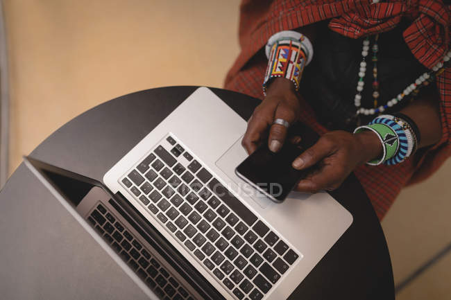 Высокоугольный вид человека масаи в традиционной одежде с помощью мобильного телефона — стоковое фото