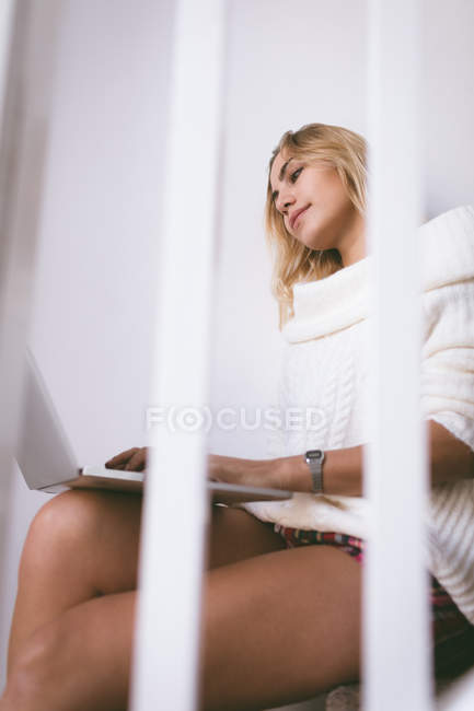 Женщина с ноутбуком, сидя дома на лестнице — стоковое фото