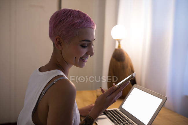 Young woman with pink hair using mobile phone at home. — Stock Photo