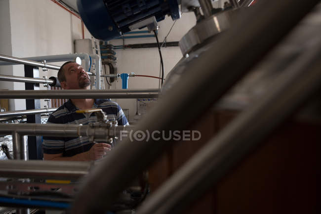 Чоловік-працівник контролює бак для зберігання на заводі джинів — стокове фото
