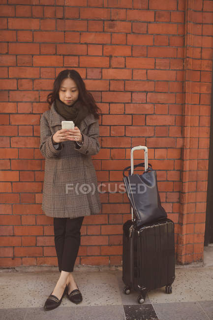 Woman using mobile phone against brick wall at railway platform — Stock Photo