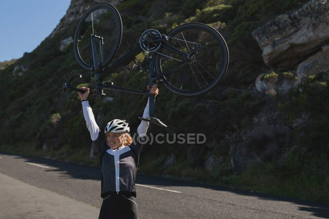 Aufgeregte Radfahrerin trägt Mountainbike auf Straße — Stockfoto