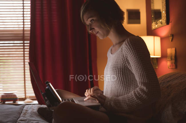 Mulher bonita usando laptop na cama no quarto em casa — Fotografia de Stock