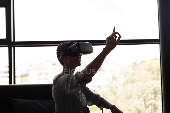 Зрелая деловая женщина, использующая гарнитуру виртуальной реальности в офисе — стоковое фото