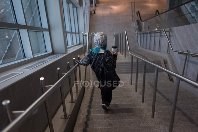 Woman moving down through staircase at station — Stock Photo