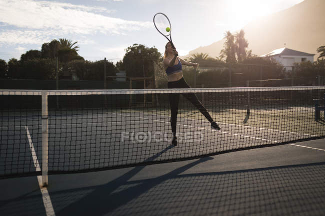 Young woman practicing tennis in the tennis court — Stock Photo