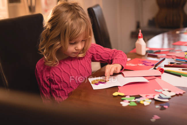 Chica preparando decoración de la forma del corazón en casa - foto de stock