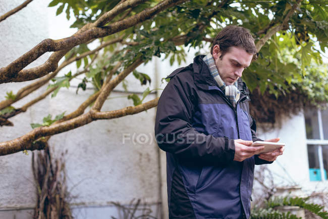 Mann benutzt digitales Tablet im Hinterhof seines Hauses — Stockfoto