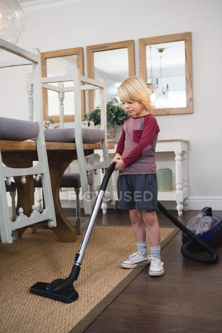 Boy using vacuum cleaner in living room at home — Stock Photo