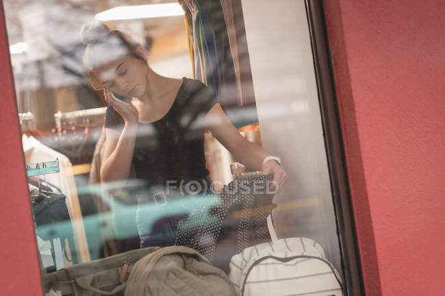Красивая девушка разговаривает по мобильному телефону во время покупок в торговом центре — стоковое фото