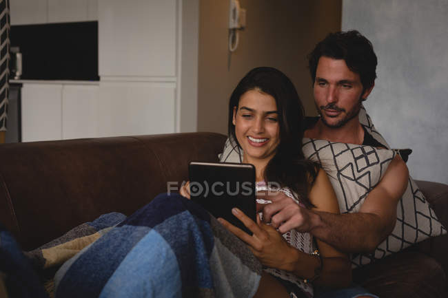 Pareja usando tableta digital en la sala de estar en casa - foto de stock