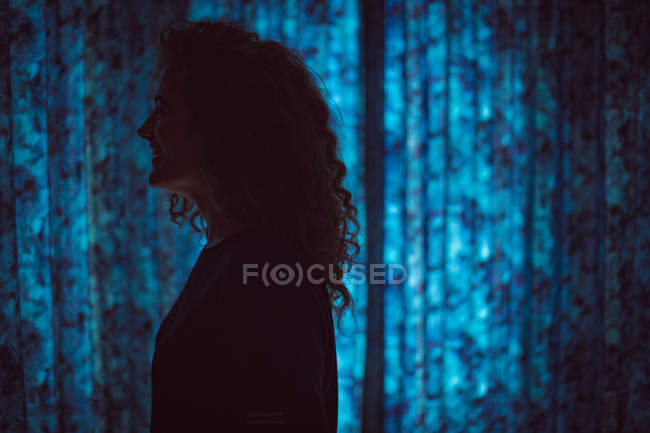 Donna sorridente in piedi in camera oscura a casa — Foto stock