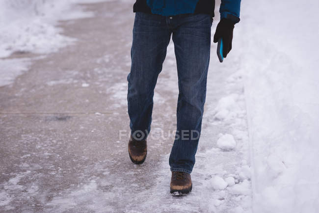Low section of man walking on snow covered pathway. — Stock Photo