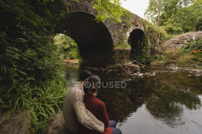 Прихильна пара сидить на березі річки — стокове фото