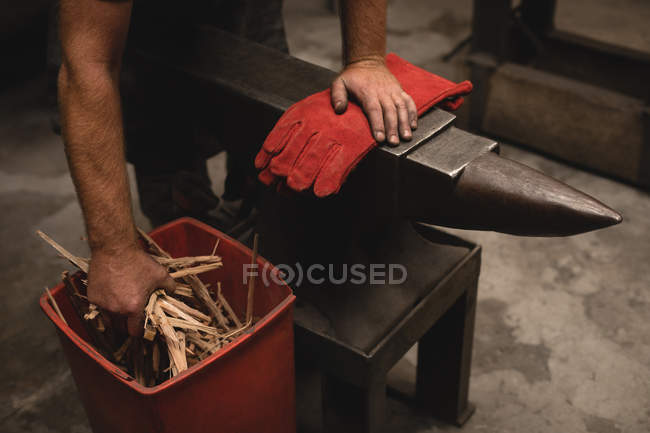 Herrero sosteniendo palos de madera en el taller - foto de stock