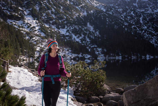 Female hiker walking at lakeside during winter — Stock Photo