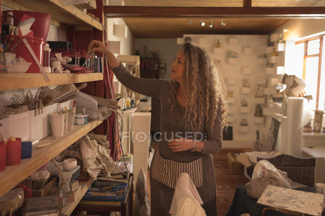 Ceramista donna che organizza attrezzature a casa — Foto stock
