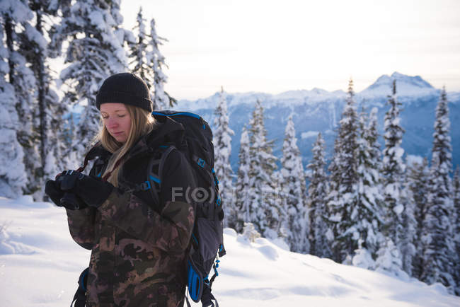 Frau in Winterkleidung überprüft Foto auf Digitalkamera an einem sonnigen Tag — Stockfoto