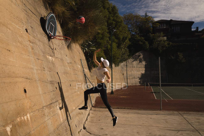 Жінка грає в баскетбол на баскетбольному майданчику в сонячний день — стокове фото