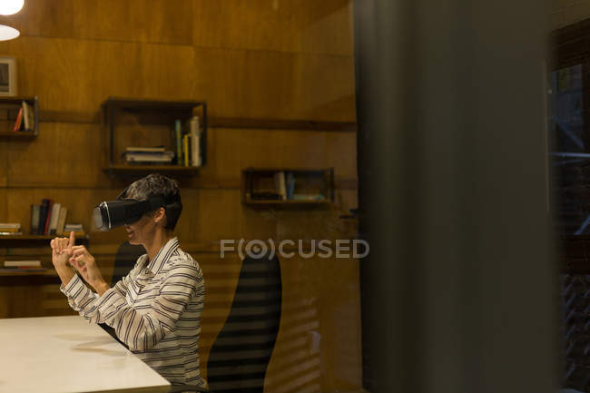 Зріла бізнес-леді, використовуючи гарнітуру віртуальної реальності в офісі — стокове фото
