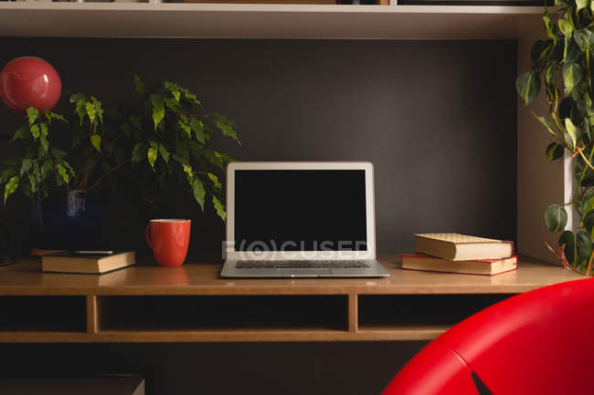 Ordenador portátil, libros y café en el gabinete en casa - foto de stock