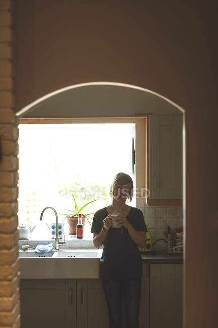 Beautiful woman having coffee in kitchen at home — Stock Photo