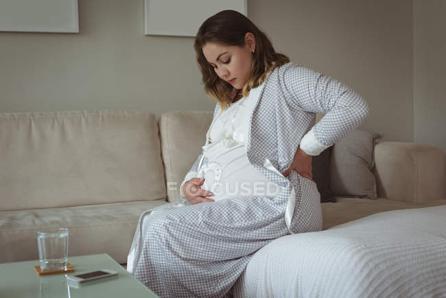 Pregnant woman touching her belly at home — Stock Photo