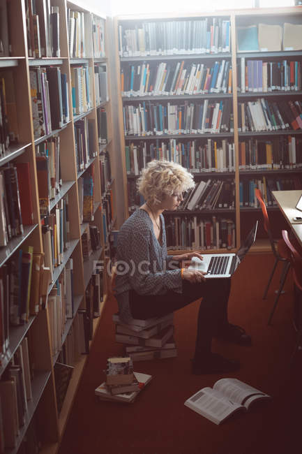 Giovane donna che utilizza il computer portatile in biblioteca — Foto stock