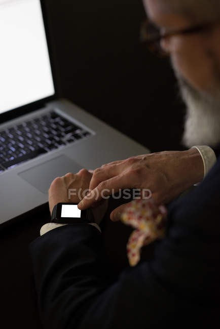 Businessman using smartwatch at desk in office — Stock Photo