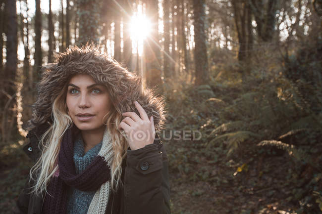 Mujer joven con capucha de pie en el bosque - foto de stock
