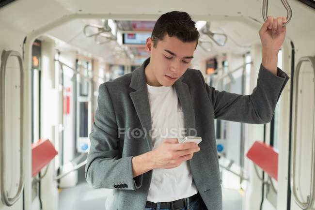 Красивий чоловік використовує мобільний телефон в автобусі — стокове фото