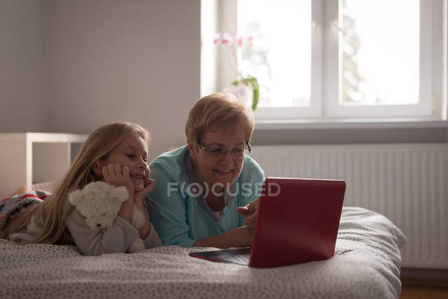 Grandmother and daughter using laptop in bedroom at home — Stock Photo