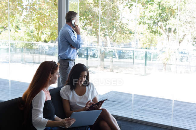 Dirigeantes discutant sur ordinateur portable et tablette numérique au bureau — Photo de stock