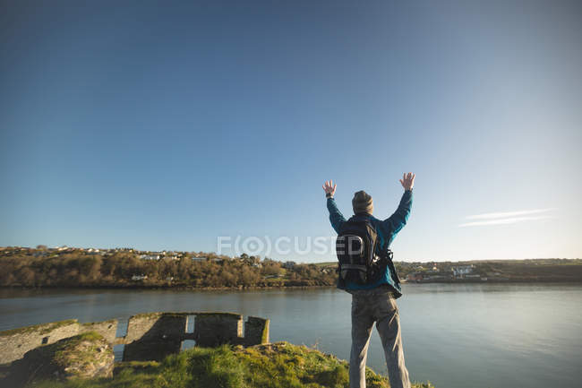 Rückansicht eines männlichen Wanderers, der mit erhobenen Armen in der Landschaft steht — Stockfoto