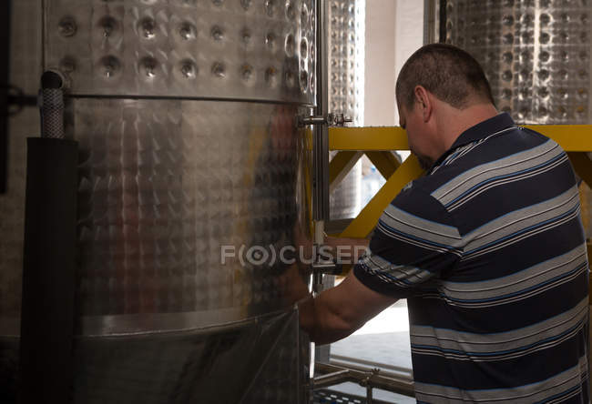 Travailleur masculin travaillant près de la distillerie dans une usine de gin — Photo de stock