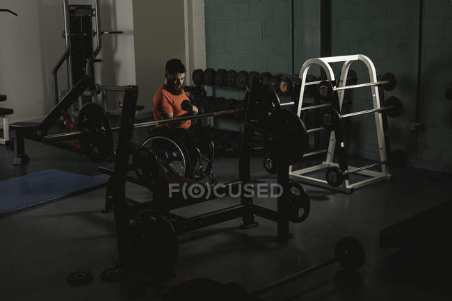 Homem deficiente em cadeira de rodas trabalhando com halteres no ginásio — Fotografia de Stock