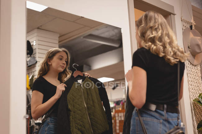 Vista trasera de la chica que comprueba la chaqueta delante del espejo - foto de stock