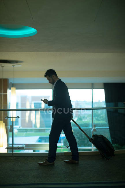 Uomo d'affari che utilizza il telefono cellulare nel corridoio in hotel — Foto stock