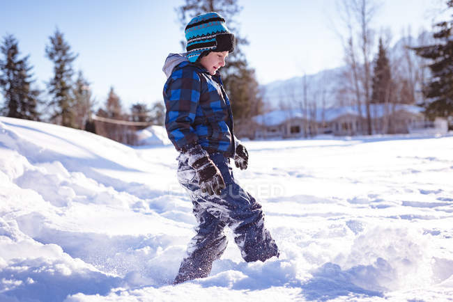 Lindo chico jugando en la nieve durante el invierno - foto de stock
