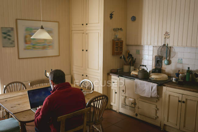 Homme attentif utilisant un ordinateur portable à la maison — Photo de stock