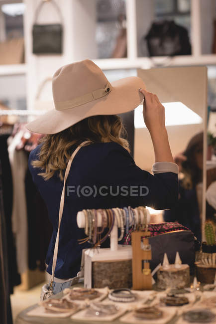 Girl trying out hat in shopping mall — Stock Photo