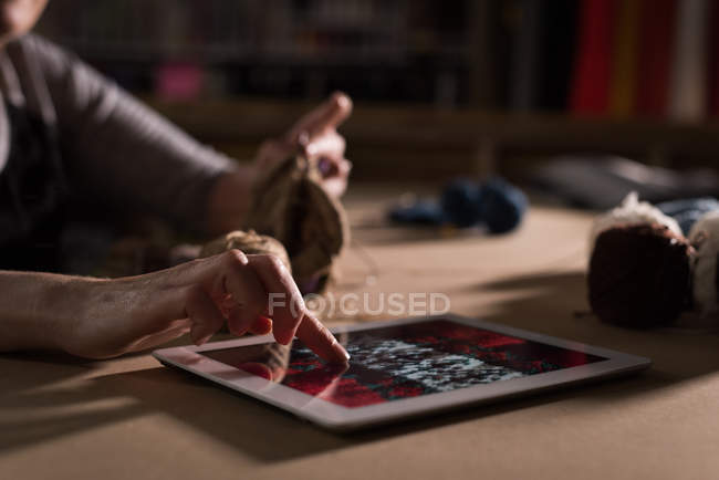 Close-up of woman knitting wool at tailor shop while using digital tablet — Stock Photo