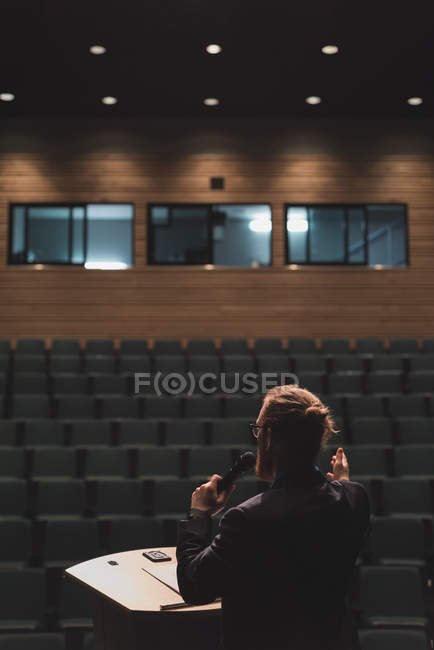 Homme pratiquant la parole avec microphone sur scène dans le théâtre . — Photo de stock