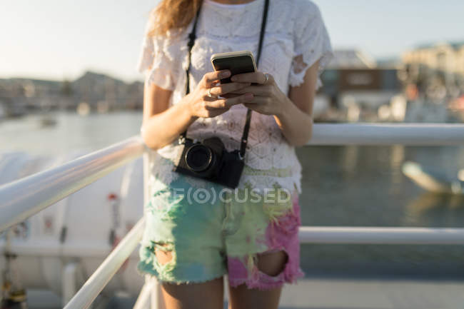 Средняя часть женщины, использующая мобильный телефон на круизном лайнере — стоковое фото