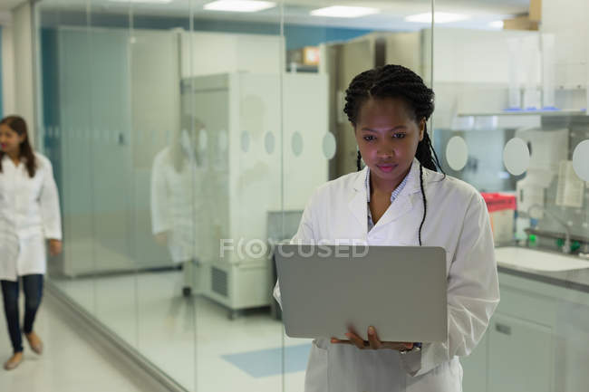 Cientista feminina usando laptop no corredor — Fotografia de Stock