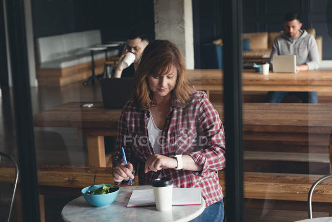 Ділова жінка пише на щоденнику в кафетерії в офісі — стокове фото