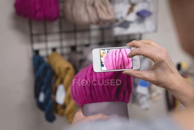 Крупним планом жінка фотографує пряжу з мобільним телефоном в крамниці кравець — стокове фото