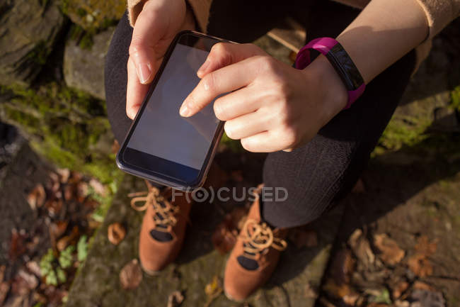 Low section of woman using mobile phone during autumn — Stock Photo