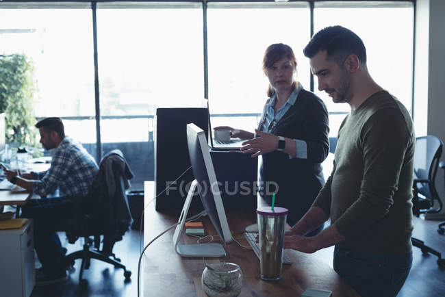 Colleghi d'affari che interagiscono tra loro mentre lavorano in ufficio — Foto stock